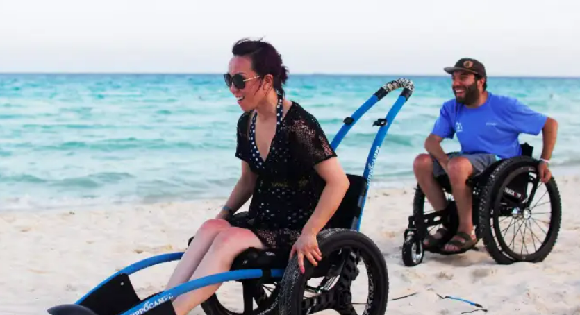 Dos personas en silla de ruedas (mujer y hombre) en la playa