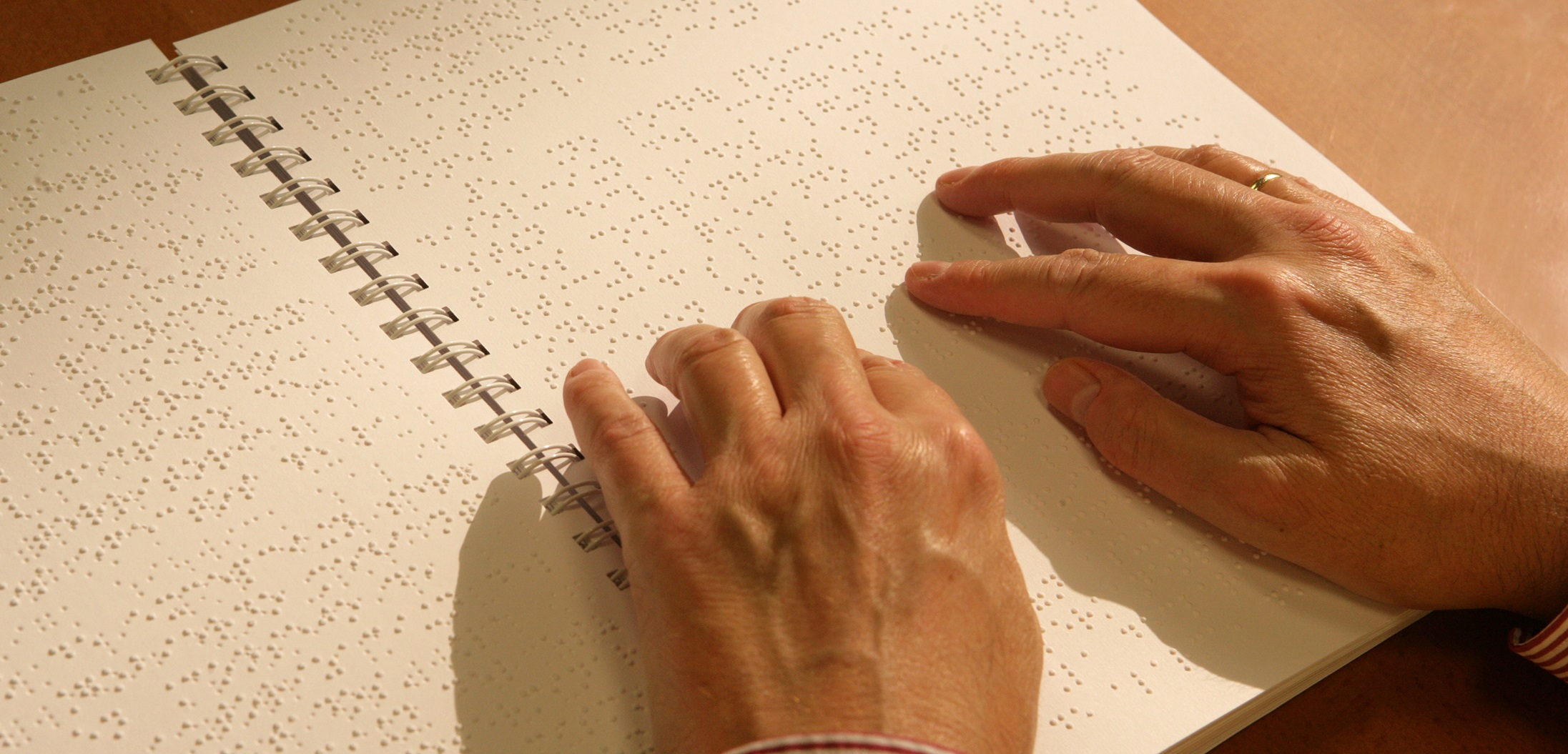 Manos de hombre leyendo un texto en braille