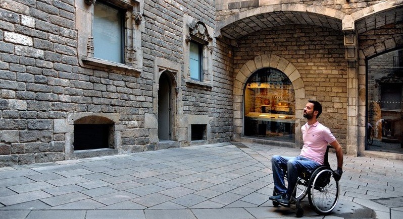Fotografía de hombre en silla de ruedas visitante un edificio histórico