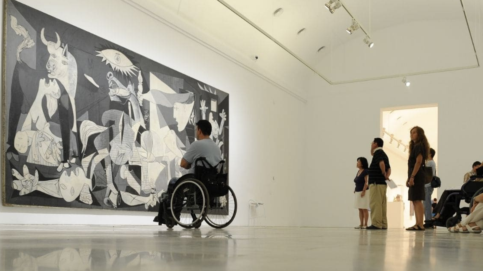 Joven en silla de ruedas contemplando un cuadro en un museo